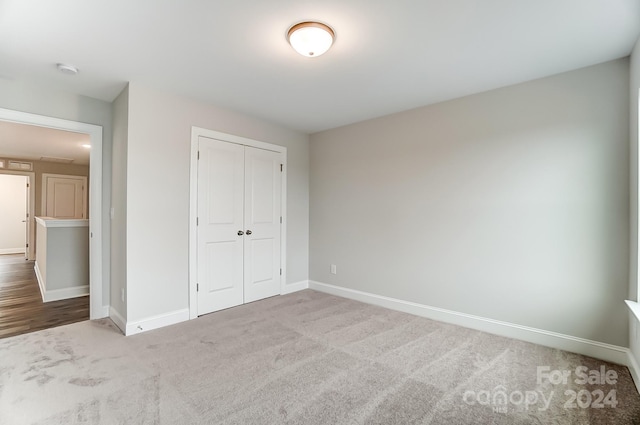 unfurnished bedroom featuring light carpet and a closet