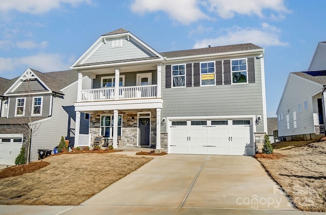 craftsman inspired home featuring a porch, a balcony, a garage, driveway, and stone siding