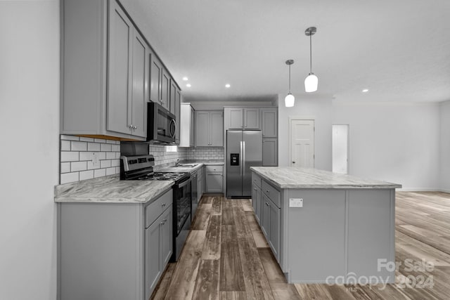 kitchen featuring pendant lighting, stainless steel appliances, light hardwood / wood-style floors, and gray cabinetry