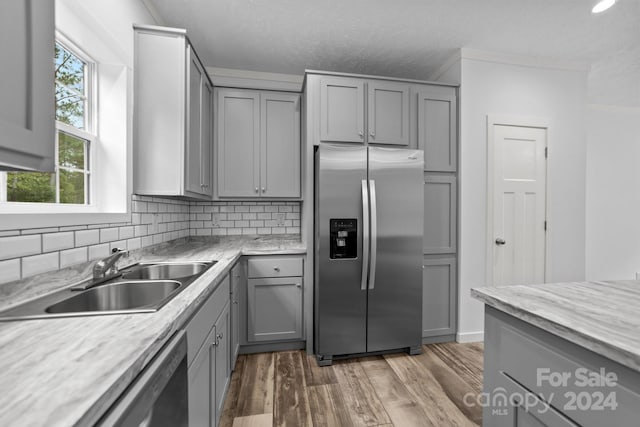 kitchen featuring sink, tasteful backsplash, gray cabinetry, appliances with stainless steel finishes, and light wood-type flooring