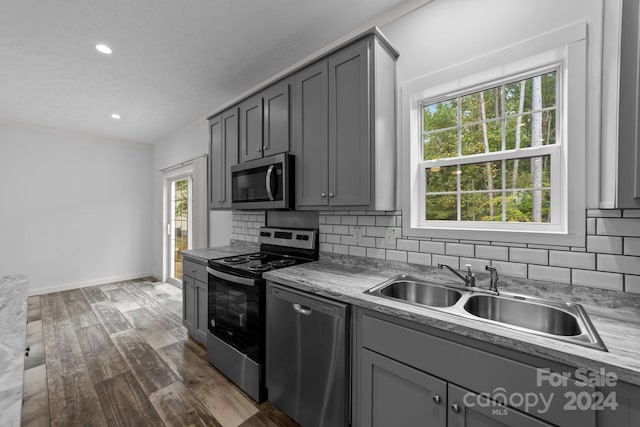 kitchen with gray cabinets, stainless steel appliances, sink, and dark hardwood / wood-style flooring