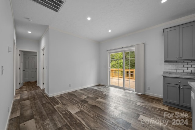 unfurnished living room with a textured ceiling, crown molding, and dark hardwood / wood-style flooring