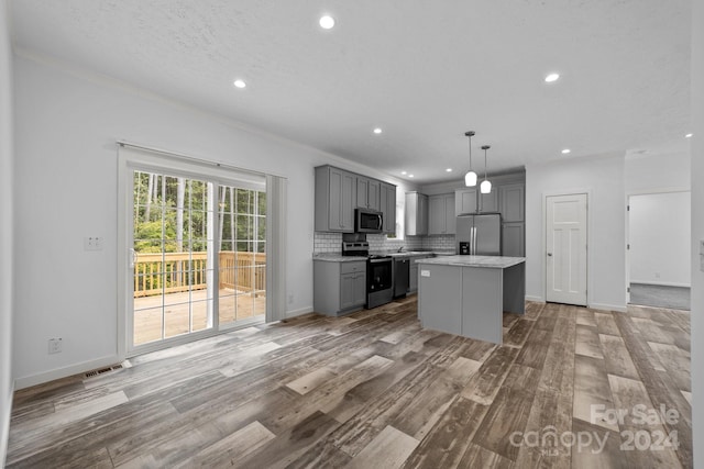 kitchen with gray cabinets, pendant lighting, a kitchen island, light hardwood / wood-style flooring, and stainless steel appliances