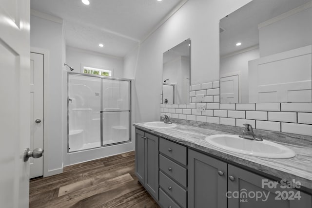 bathroom with an enclosed shower, hardwood / wood-style flooring, vanity, and tasteful backsplash