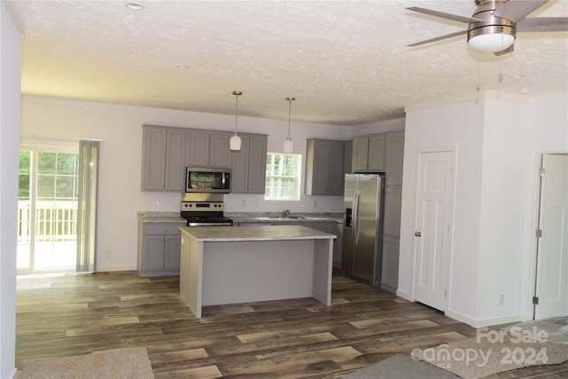 kitchen featuring appliances with stainless steel finishes, hanging light fixtures, dark wood-type flooring, and ceiling fan