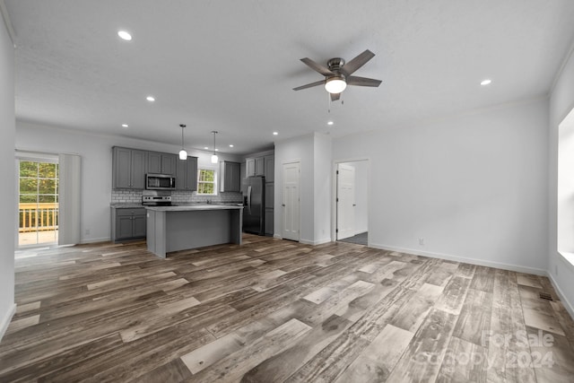 kitchen with pendant lighting, gray cabinets, stainless steel appliances, wood-type flooring, and a center island