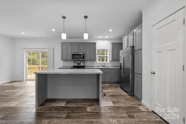 kitchen with pendant lighting, gray cabinetry, dark wood-type flooring, stainless steel appliances, and decorative backsplash