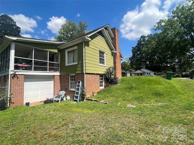 view of side of property with a sunroom, a garage, a yard, and central air condition unit