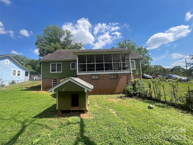 rear view of house featuring a yard and a sunroom