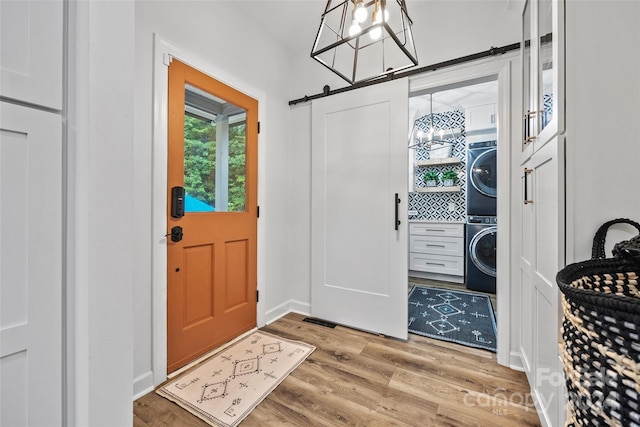 entryway featuring stacked washer and clothes dryer, a barn door, and hardwood / wood-style floors