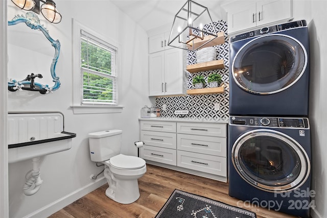 bathroom featuring stacked washer and dryer, toilet, wood-type flooring, vanity, and decorative backsplash