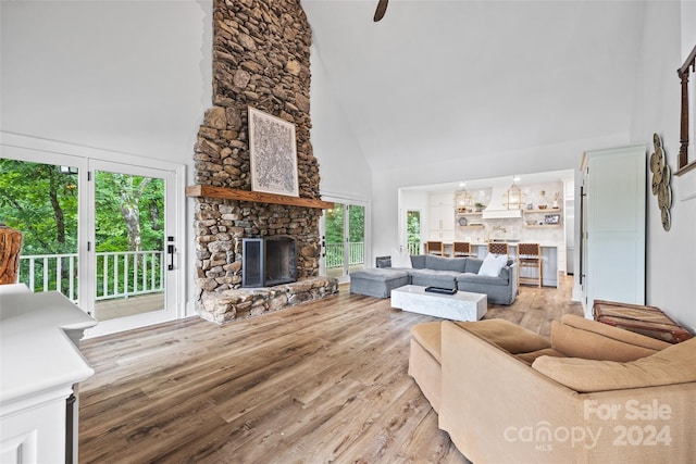 living room featuring a high ceiling, a stone fireplace, and light hardwood / wood-style floors