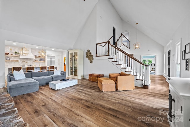 living room featuring an inviting chandelier, hardwood / wood-style floors, and high vaulted ceiling