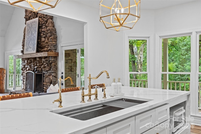 kitchen with sink, white cabinetry, an inviting chandelier, decorative light fixtures, and a wealth of natural light