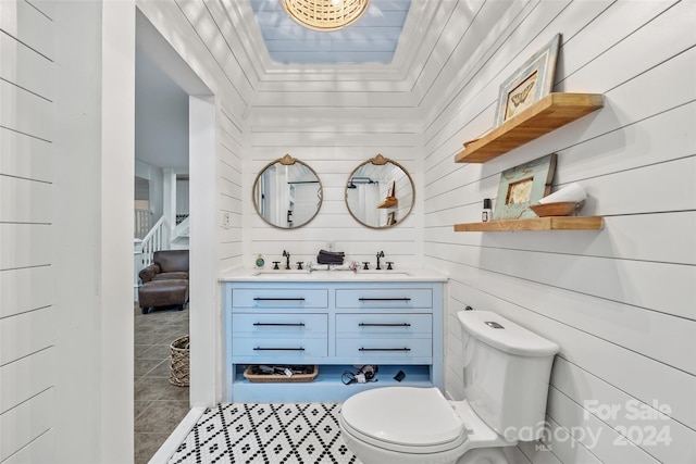 bathroom featuring vanity, wooden walls, tile patterned flooring, and toilet