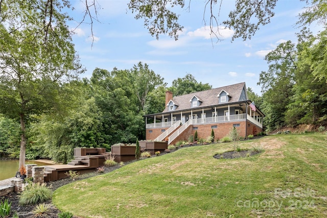 rear view of property featuring a hot tub, a deck, a sunroom, and a lawn