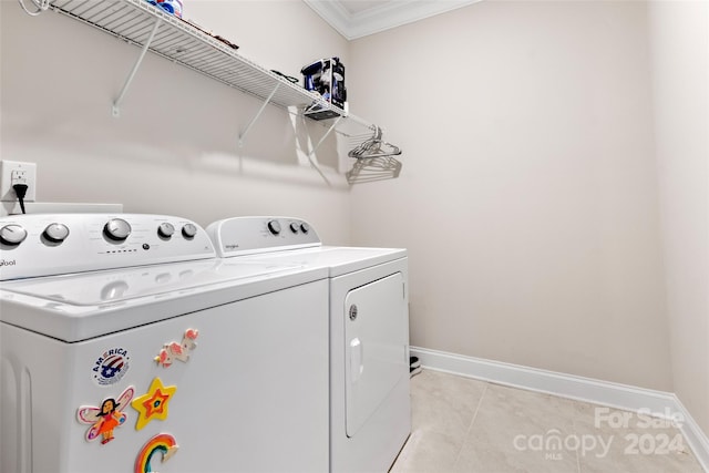 washroom featuring light tile flooring, crown molding, and washing machine and dryer