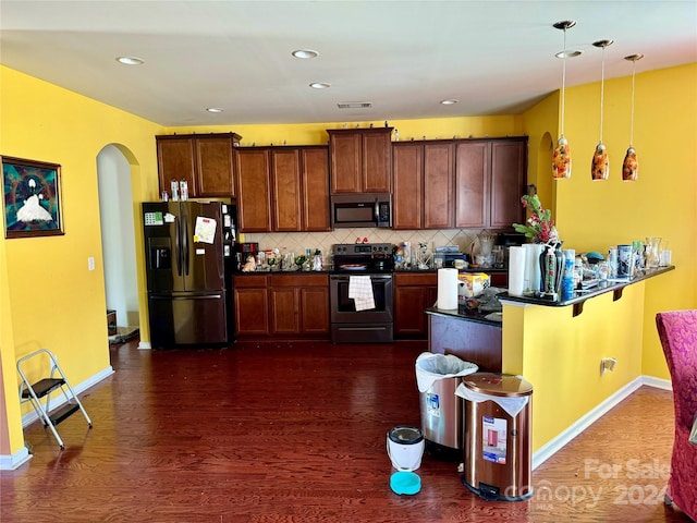 kitchen with kitchen peninsula, appliances with stainless steel finishes, backsplash, dark wood-type flooring, and decorative light fixtures