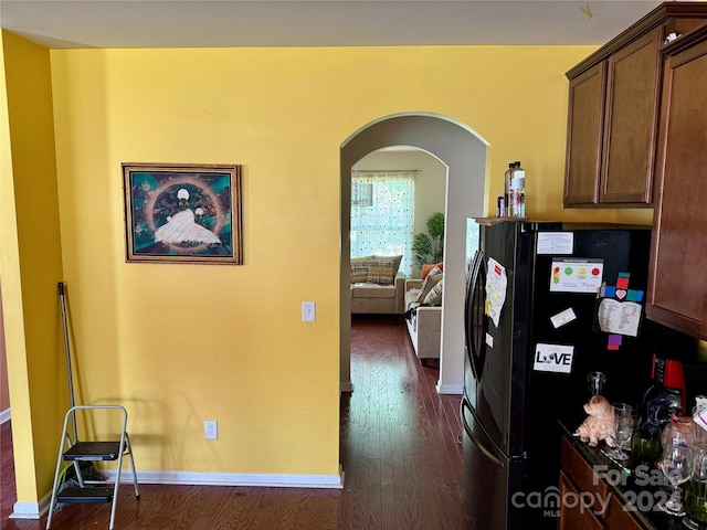 kitchen with dark hardwood / wood-style floors and black fridge