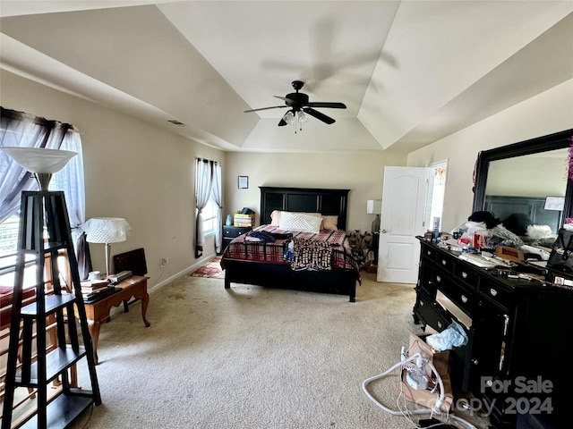 bedroom featuring a tray ceiling, multiple windows, ceiling fan, and light carpet