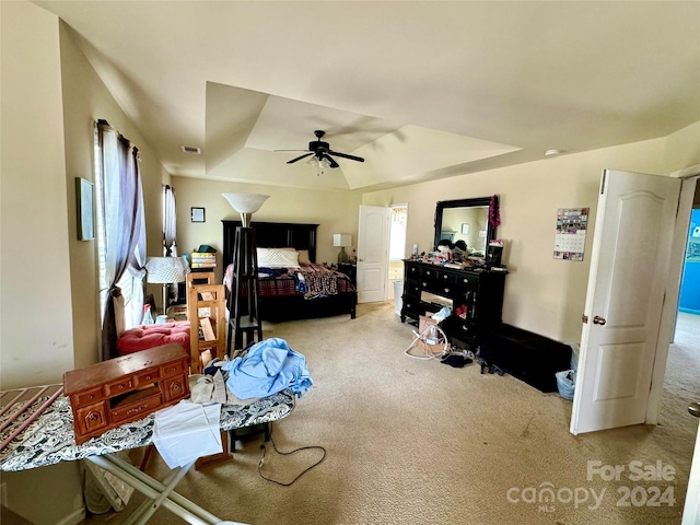 bedroom featuring light carpet, a tray ceiling, and ceiling fan