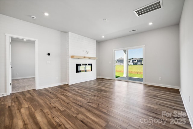 unfurnished living room featuring dark hardwood / wood-style flooring and a large fireplace