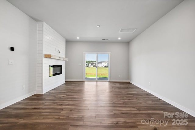 unfurnished living room with a large fireplace and dark wood-type flooring