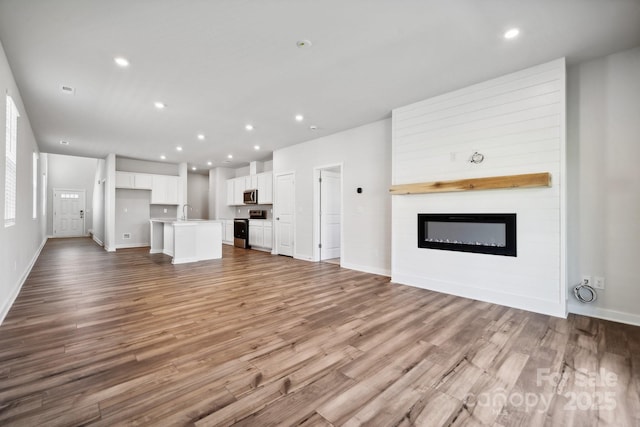 unfurnished living room featuring a fireplace, light hardwood / wood-style flooring, and sink