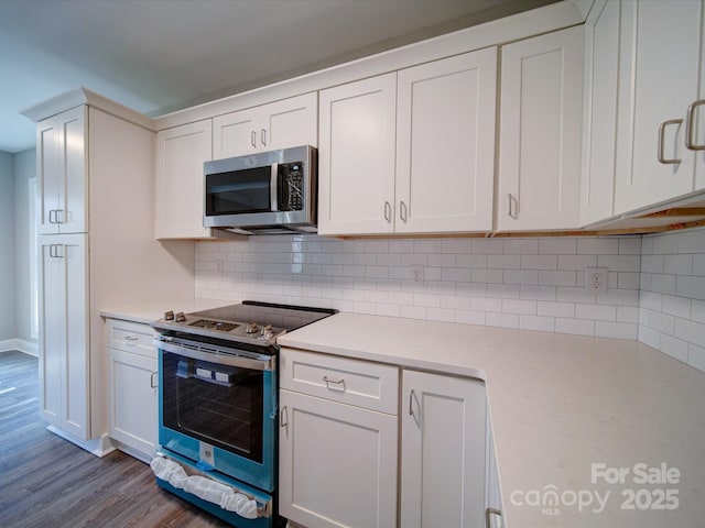 kitchen with stainless steel appliances, white cabinetry, tasteful backsplash, and hardwood / wood-style flooring