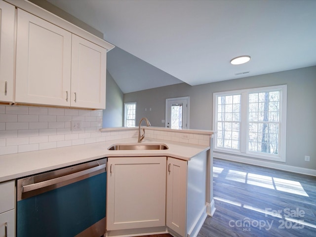 kitchen featuring white cabinets, dishwasher, kitchen peninsula, sink, and tasteful backsplash