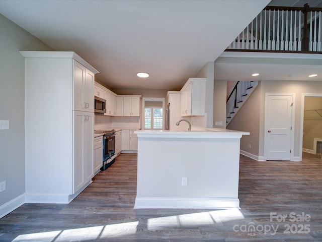 kitchen featuring stainless steel appliances, kitchen peninsula, sink, white cabinetry, and backsplash