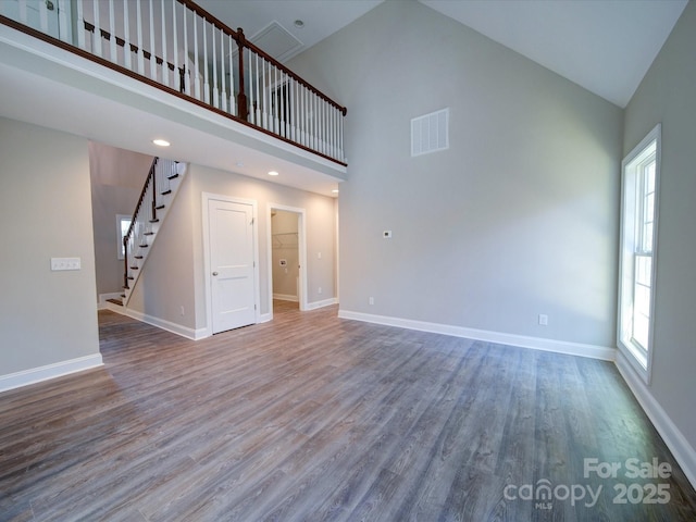 unfurnished living room featuring high vaulted ceiling, a wealth of natural light, and hardwood / wood-style floors