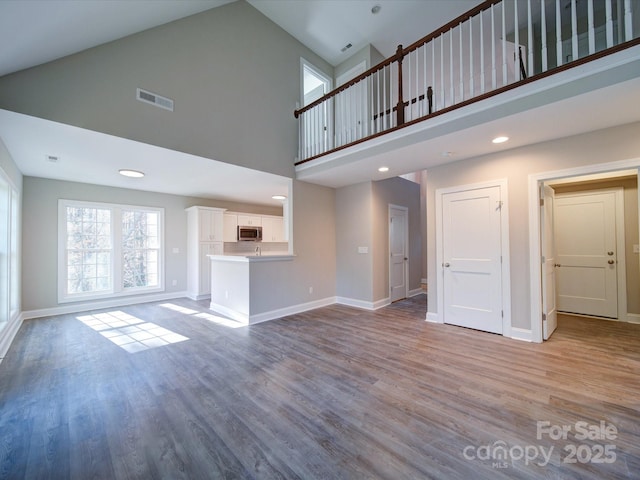 unfurnished living room featuring high vaulted ceiling and wood-type flooring