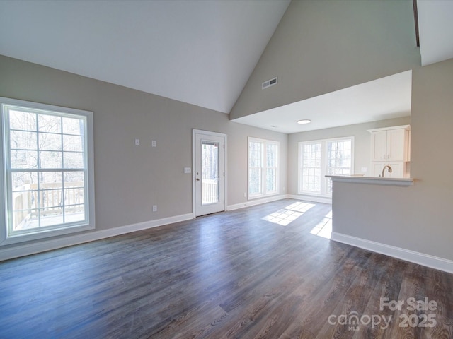 unfurnished living room featuring high vaulted ceiling and dark hardwood / wood-style floors