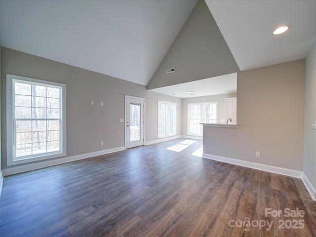 unfurnished living room with high vaulted ceiling and dark hardwood / wood-style flooring