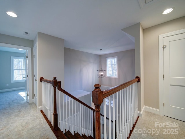 hallway with a notable chandelier, a healthy amount of sunlight, and carpet floors