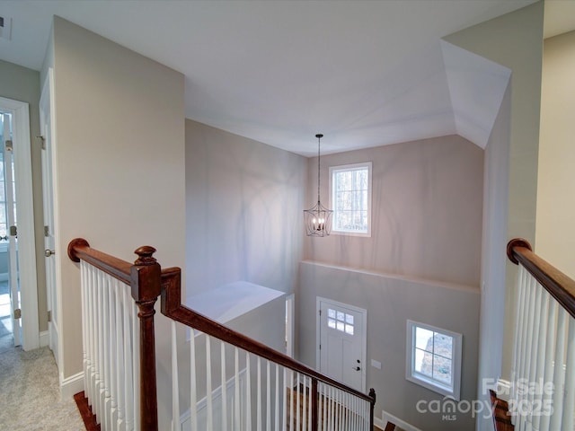 corridor featuring a notable chandelier and vaulted ceiling