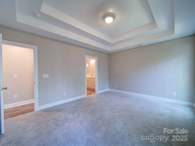 empty room featuring carpet and a tray ceiling