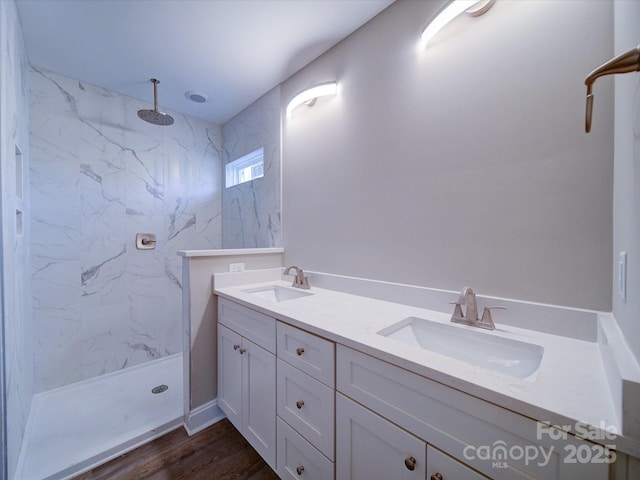 bathroom featuring hardwood / wood-style flooring, tiled shower, and vanity