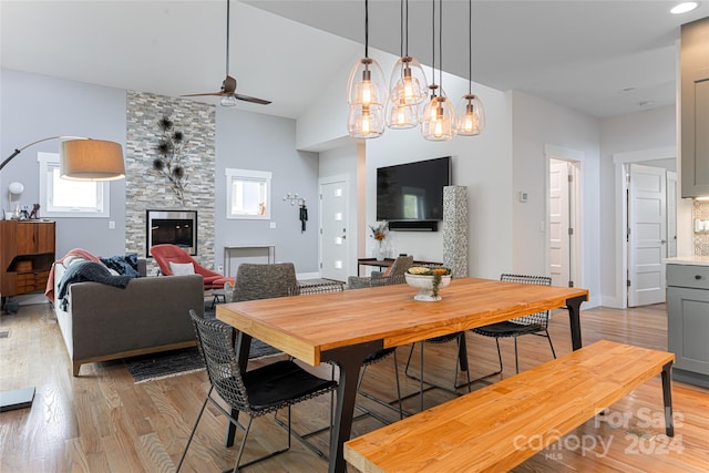 dining room featuring ceiling fan with notable chandelier, light hardwood / wood-style flooring, and a fireplace