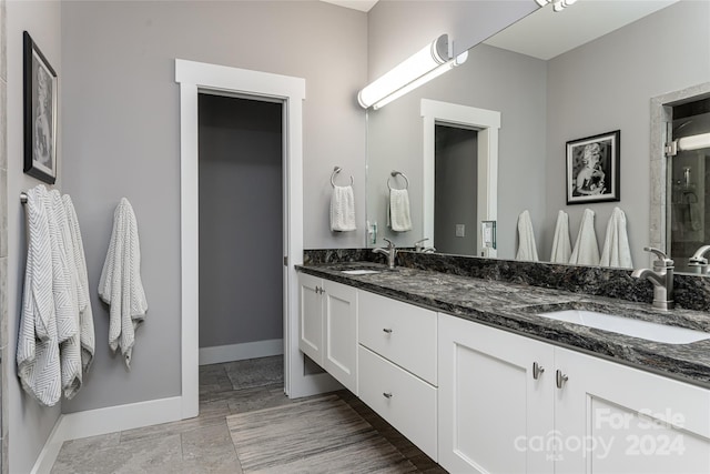 bathroom with walk in shower, tile flooring, and double sink vanity