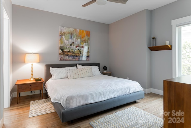 bedroom with ceiling fan, multiple windows, and light hardwood / wood-style flooring