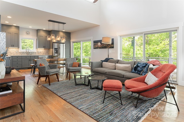 living area with light wood-style flooring, a towering ceiling, and recessed lighting
