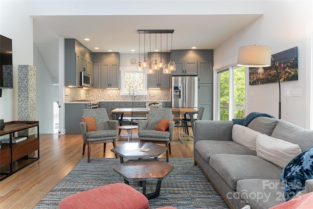 living room featuring light wood finished floors, plenty of natural light, and a notable chandelier