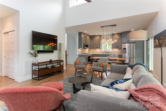 living room with an inviting chandelier, light wood finished floors, and visible vents