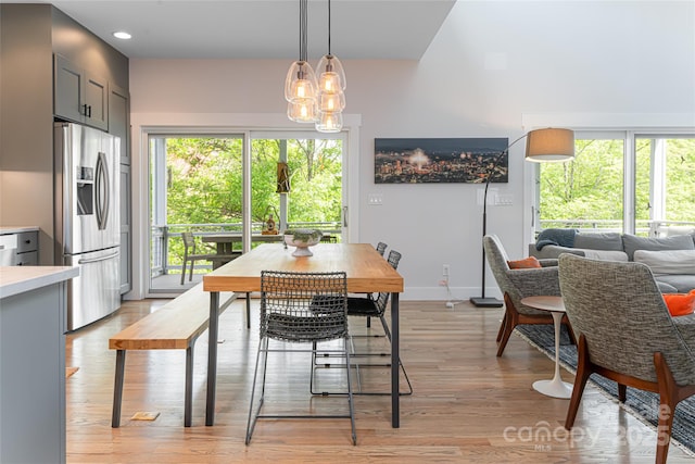 dining area with baseboards, light wood-type flooring, and a chandelier