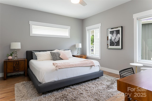 bedroom with light wood-style floors, ceiling fan, and baseboards