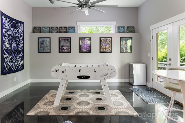 game room with finished concrete flooring, ceiling fan, and baseboards