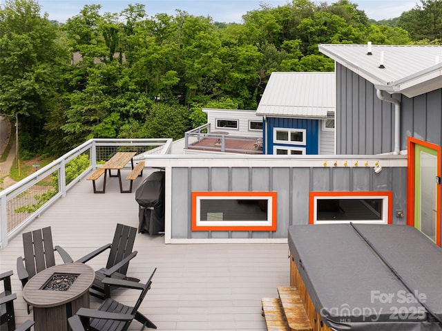 wooden deck with a fire pit and area for grilling