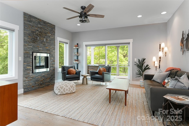 living room with baseboards, a ceiling fan, a fireplace, recessed lighting, and wood finished floors